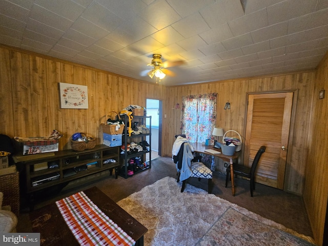 carpeted office space featuring wooden walls and ceiling fan