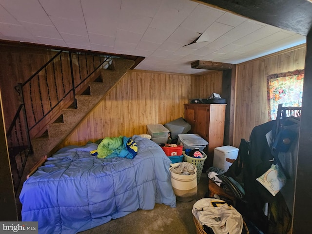 carpeted bedroom featuring wood walls