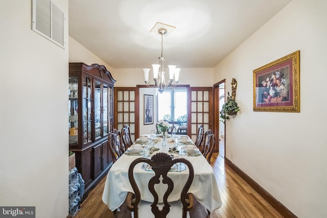 dining area featuring hardwood / wood-style flooring and an inviting chandelier