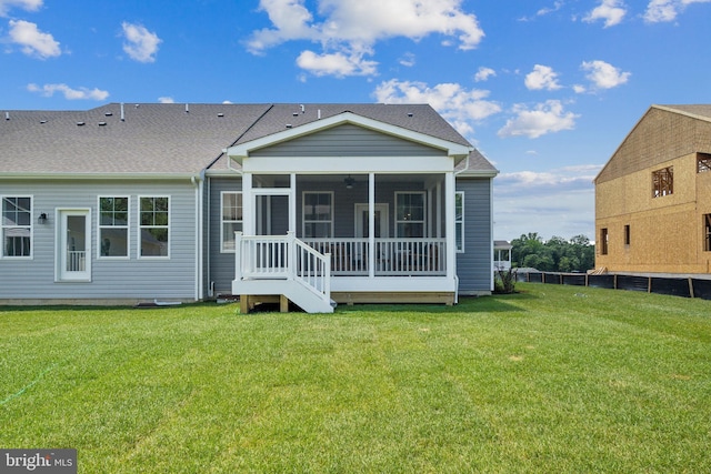 rear view of house featuring a lawn and a sunroom