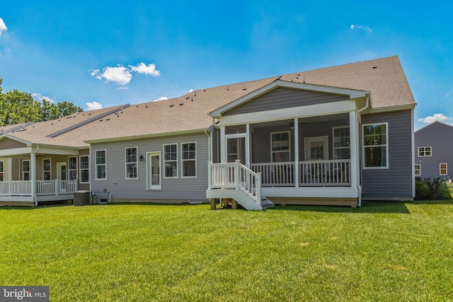 rear view of property with central air condition unit, a sunroom, and a yard