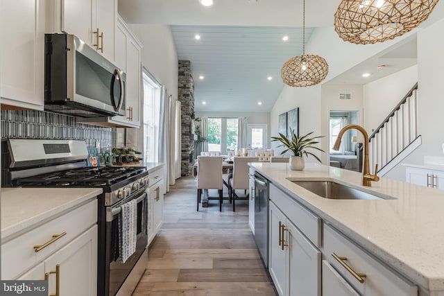 kitchen featuring stainless steel appliances, light stone countertops, sink, hardwood / wood-style flooring, and white cabinets