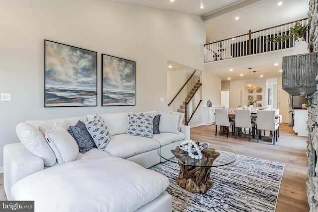 living room featuring light hardwood / wood-style flooring, a chandelier, and a high ceiling