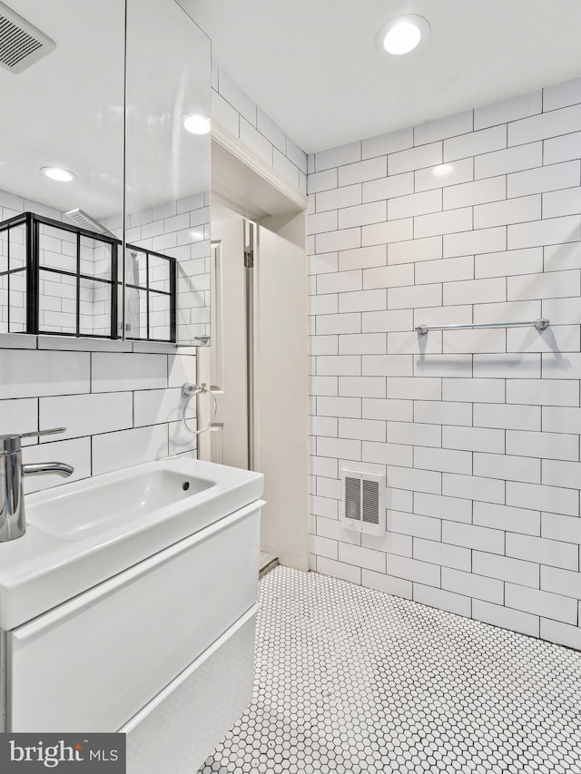 bathroom with tile walls, vanity, and a tile shower