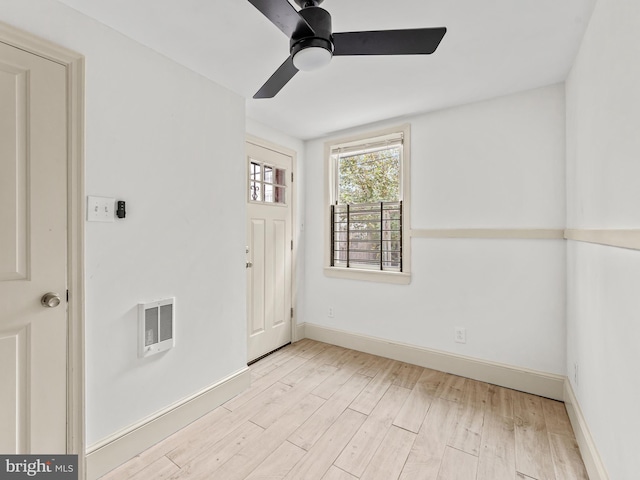 empty room featuring ceiling fan, heating unit, and light hardwood / wood-style flooring