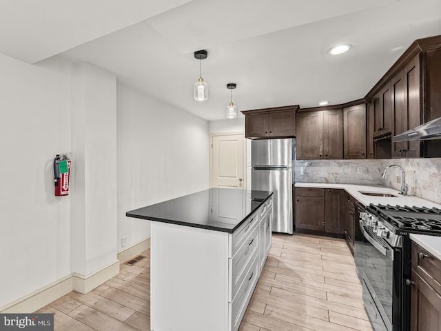 kitchen featuring decorative backsplash, sink, dark brown cabinets, light wood-type flooring, and appliances with stainless steel finishes