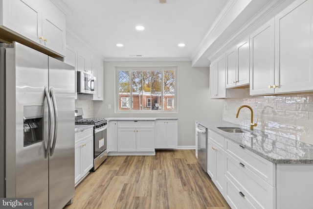 kitchen with white cabinetry, stainless steel appliances, sink, and light stone counters