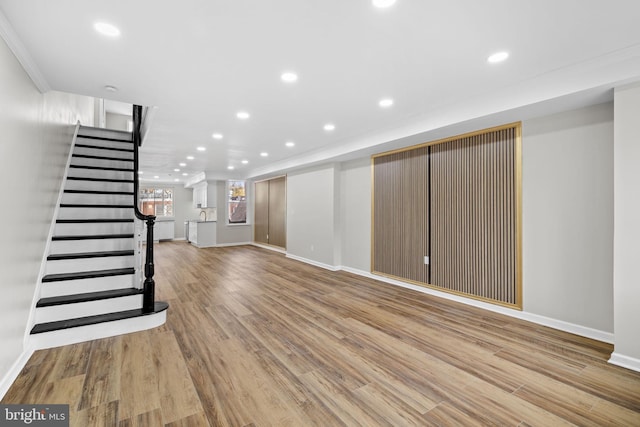 basement featuring light wood-type flooring and crown molding