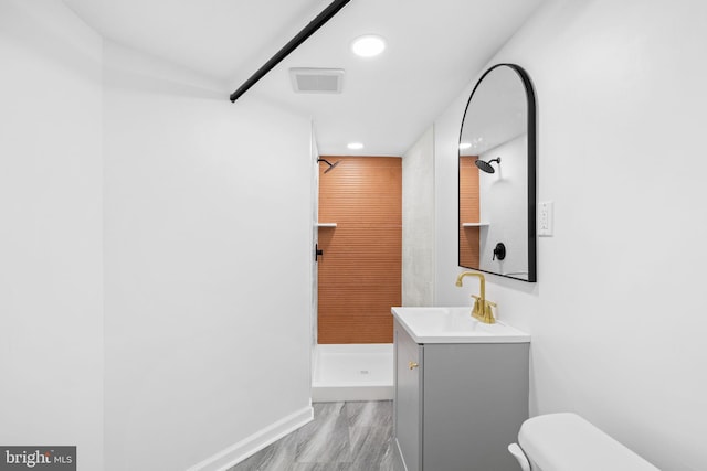 bathroom featuring a shower, hardwood / wood-style flooring, vanity, and toilet