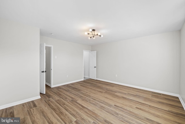 spare room with wood-type flooring and a notable chandelier