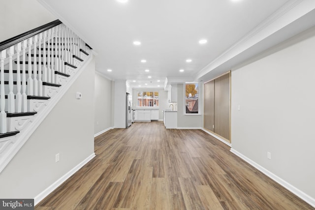 unfurnished living room with hardwood / wood-style floors, sink, and ornamental molding