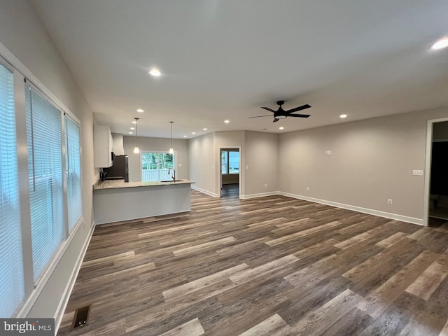 unfurnished living room featuring dark hardwood / wood-style floors, ceiling fan, and sink