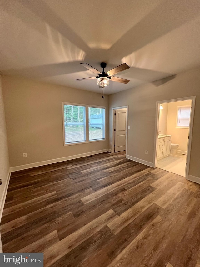 unfurnished bedroom with ceiling fan, ensuite bathroom, and dark hardwood / wood-style floors