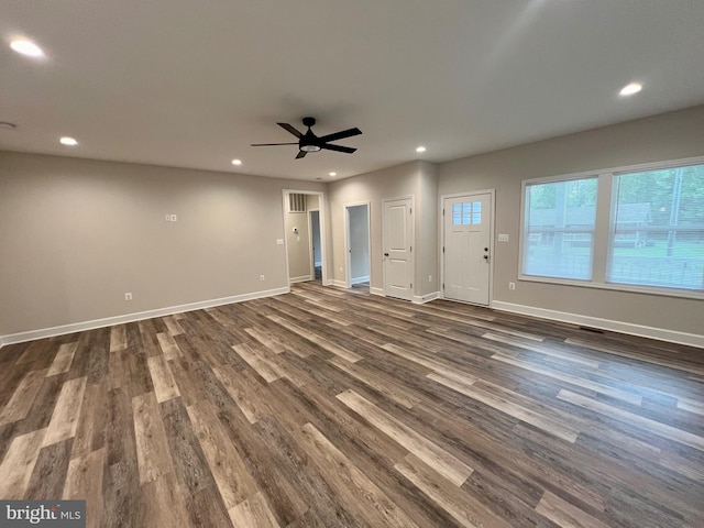 unfurnished living room featuring ceiling fan and dark wood-type flooring