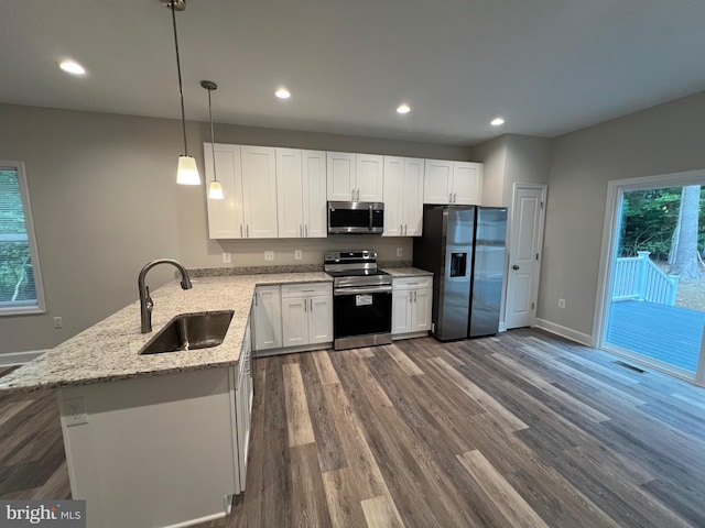 kitchen with dark wood-type flooring, hanging light fixtures, kitchen peninsula, white cabinets, and appliances with stainless steel finishes