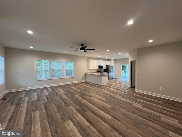 unfurnished living room featuring ceiling fan and dark hardwood / wood-style floors