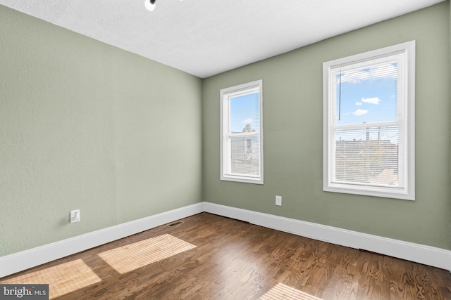 unfurnished room featuring hardwood / wood-style floors, plenty of natural light, and a textured ceiling