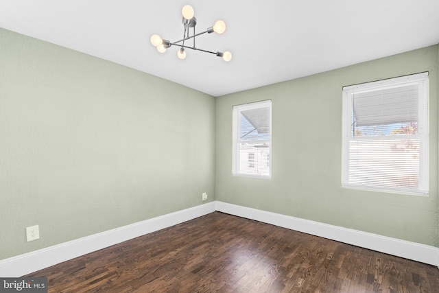 empty room featuring dark hardwood / wood-style floors and a chandelier