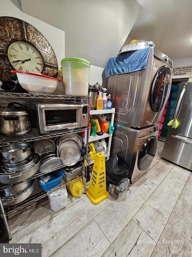 room details with light wood-type flooring and stacked washer / dryer