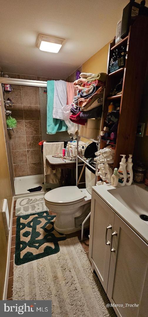 bathroom featuring tiled shower, vanity, tile patterned floors, and toilet