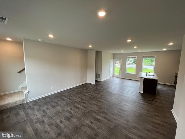 unfurnished living room featuring sink and dark wood-type flooring