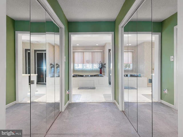 corridor with light colored carpet and a textured ceiling