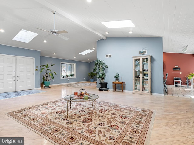 living room featuring vaulted ceiling with skylight, ceiling fan, and light hardwood / wood-style floors