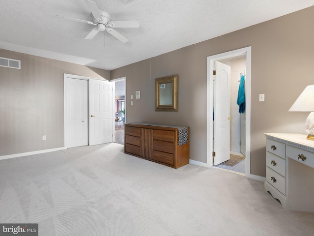 carpeted bedroom with a textured ceiling, connected bathroom, ceiling fan, and a closet