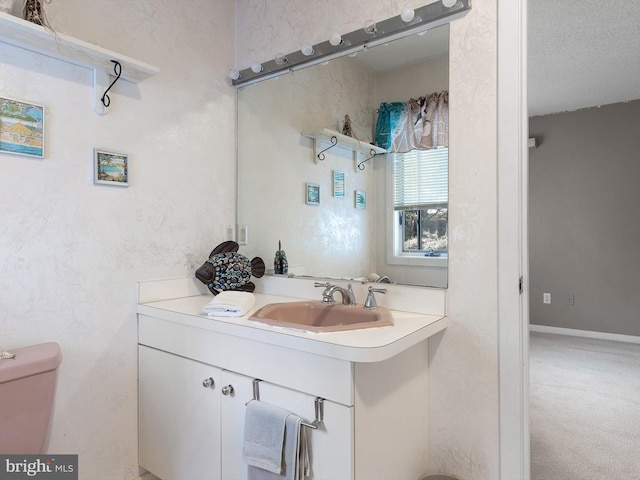 bathroom with toilet, vanity, and a textured ceiling