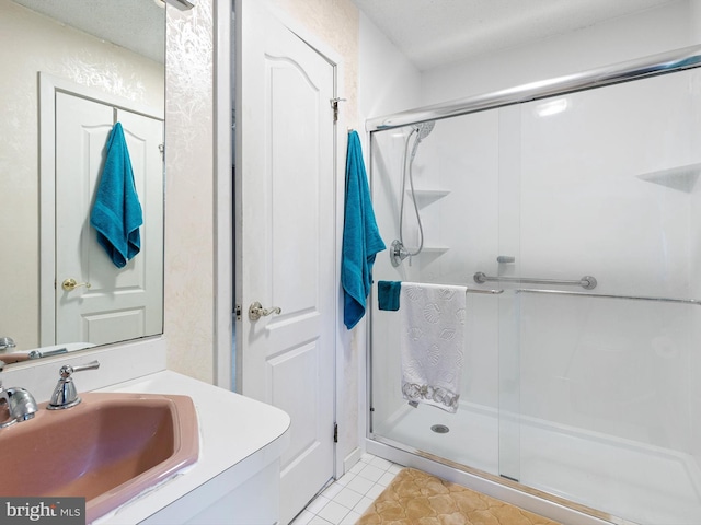 bathroom with vanity, a textured ceiling, tile patterned flooring, and a shower with shower door