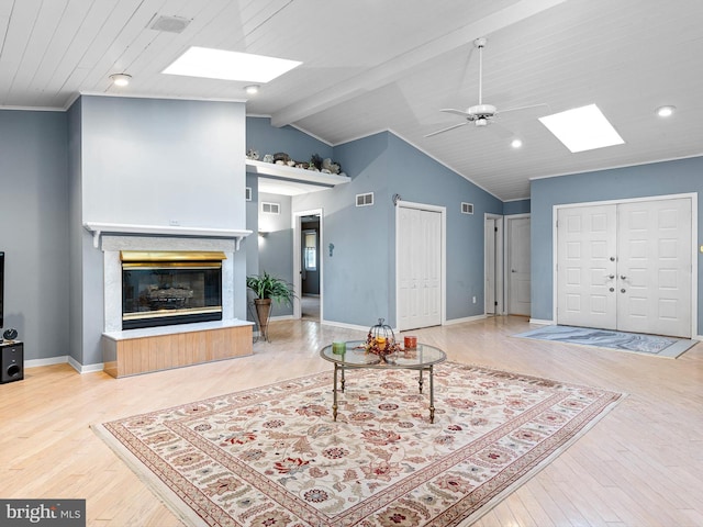 living room featuring lofted ceiling with skylight, hardwood / wood-style floors, and ceiling fan