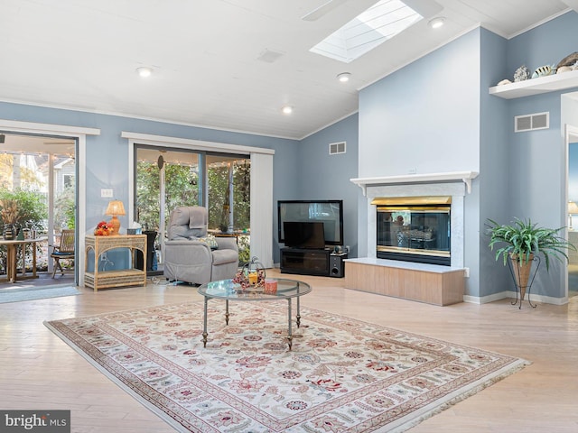 living room with ornamental molding, a skylight, hardwood / wood-style flooring, and a healthy amount of sunlight