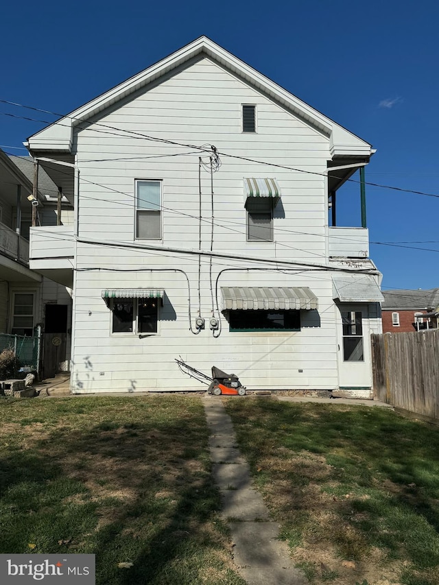 back of house with a lawn and a balcony