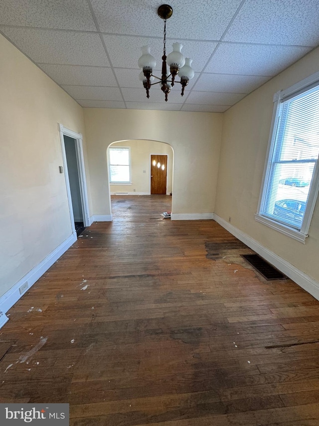 unfurnished dining area featuring dark wood-type flooring, a chandelier, and a healthy amount of sunlight