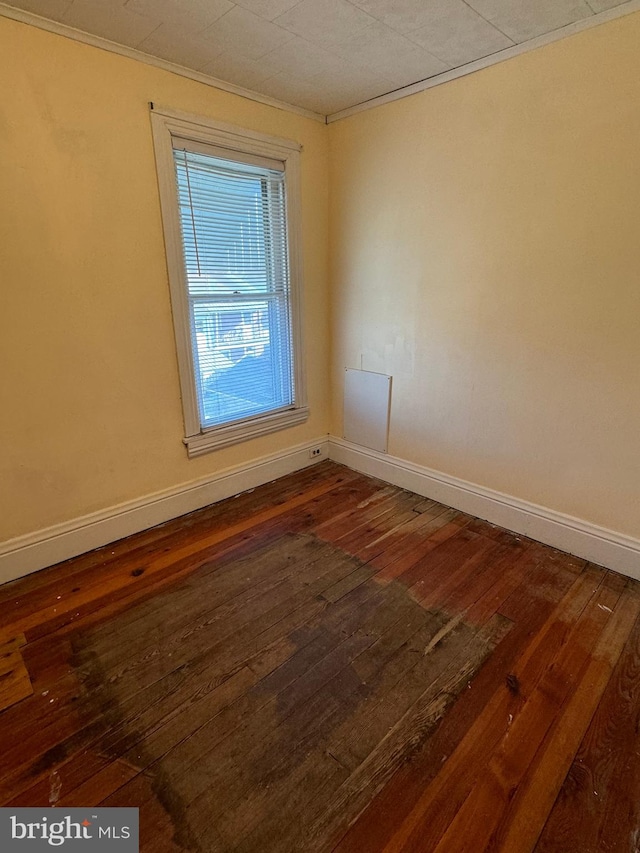 empty room featuring dark hardwood / wood-style flooring and crown molding