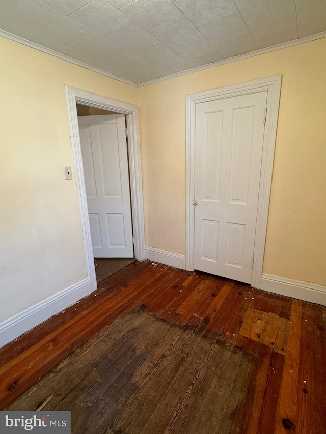 unfurnished bedroom with crown molding, a closet, and dark hardwood / wood-style flooring