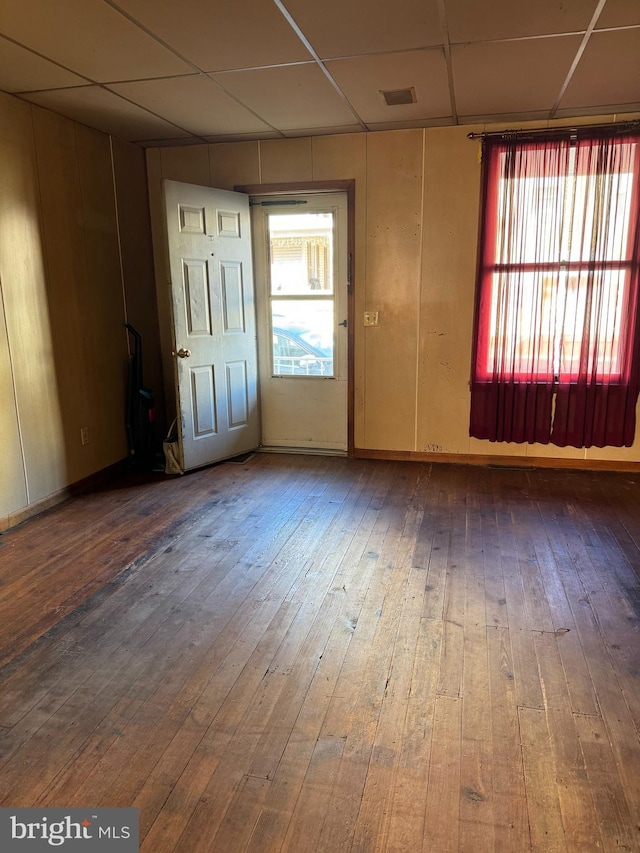 empty room featuring a drop ceiling and hardwood / wood-style floors