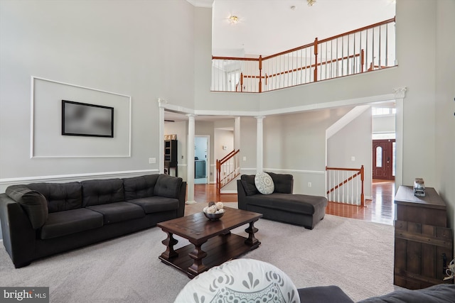 living room with ornate columns, hardwood / wood-style floors, and a towering ceiling