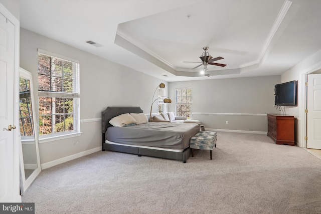 bedroom with ceiling fan, light colored carpet, ornamental molding, and a tray ceiling