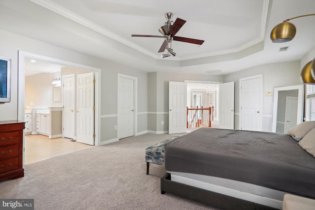 bedroom featuring light carpet, crown molding, ceiling fan, connected bathroom, and a tray ceiling