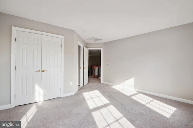 unfurnished bedroom with light colored carpet and a closet