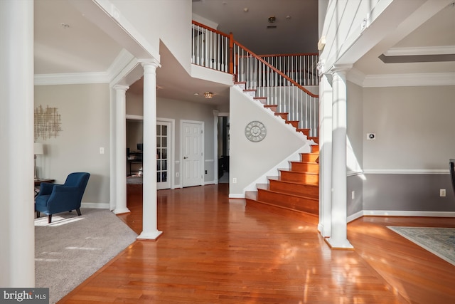 foyer with decorative columns, crown molding, and hardwood / wood-style floors