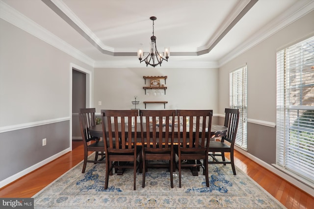 dining area featuring hardwood / wood-style floors, plenty of natural light, crown molding, and an inviting chandelier