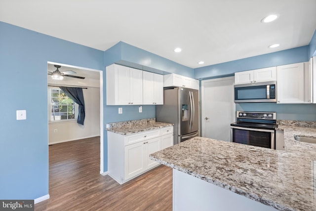 kitchen featuring white cabinetry, appliances with stainless steel finishes, hardwood / wood-style floors, and light stone countertops