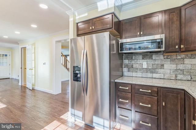 12700 Macduff Dr, Fort Washington, MD 20744 - kitchen with appliances with stainless steel finishes, ornamental molding, dark brown cabinetry, decorative backsplash, and light stone counters