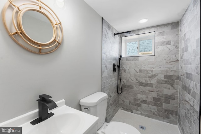 bathroom with vanity, toilet, and a tile shower