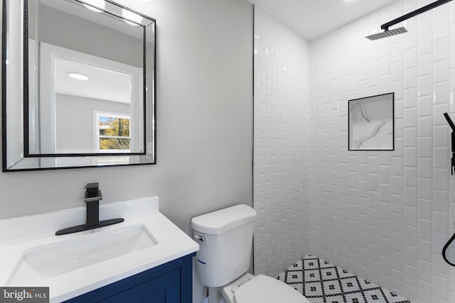 bathroom with toilet, vanity, and a tile shower