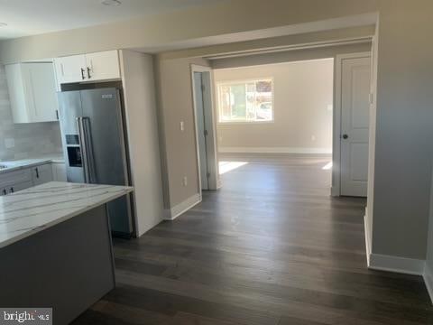 kitchen featuring white cabinets, dark hardwood / wood-style floors, light stone counters, and high end fridge