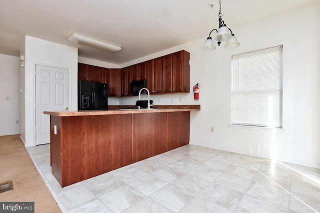 kitchen featuring kitchen peninsula, a chandelier, hanging light fixtures, and black appliances