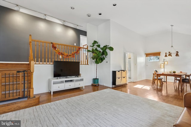 living room with high vaulted ceiling, wood-type flooring, and rail lighting